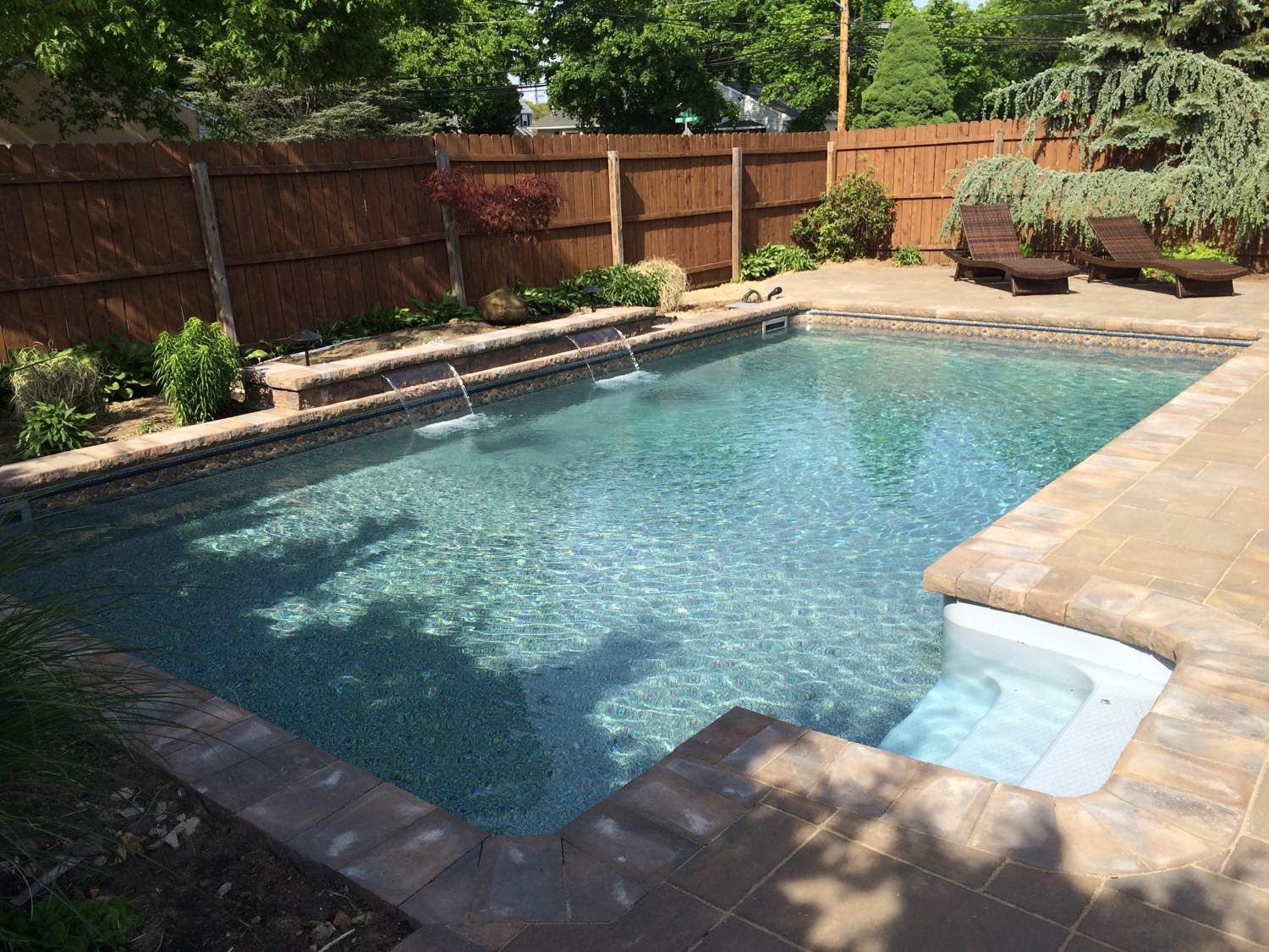 A large swimming pool with a wooden fence in the background.