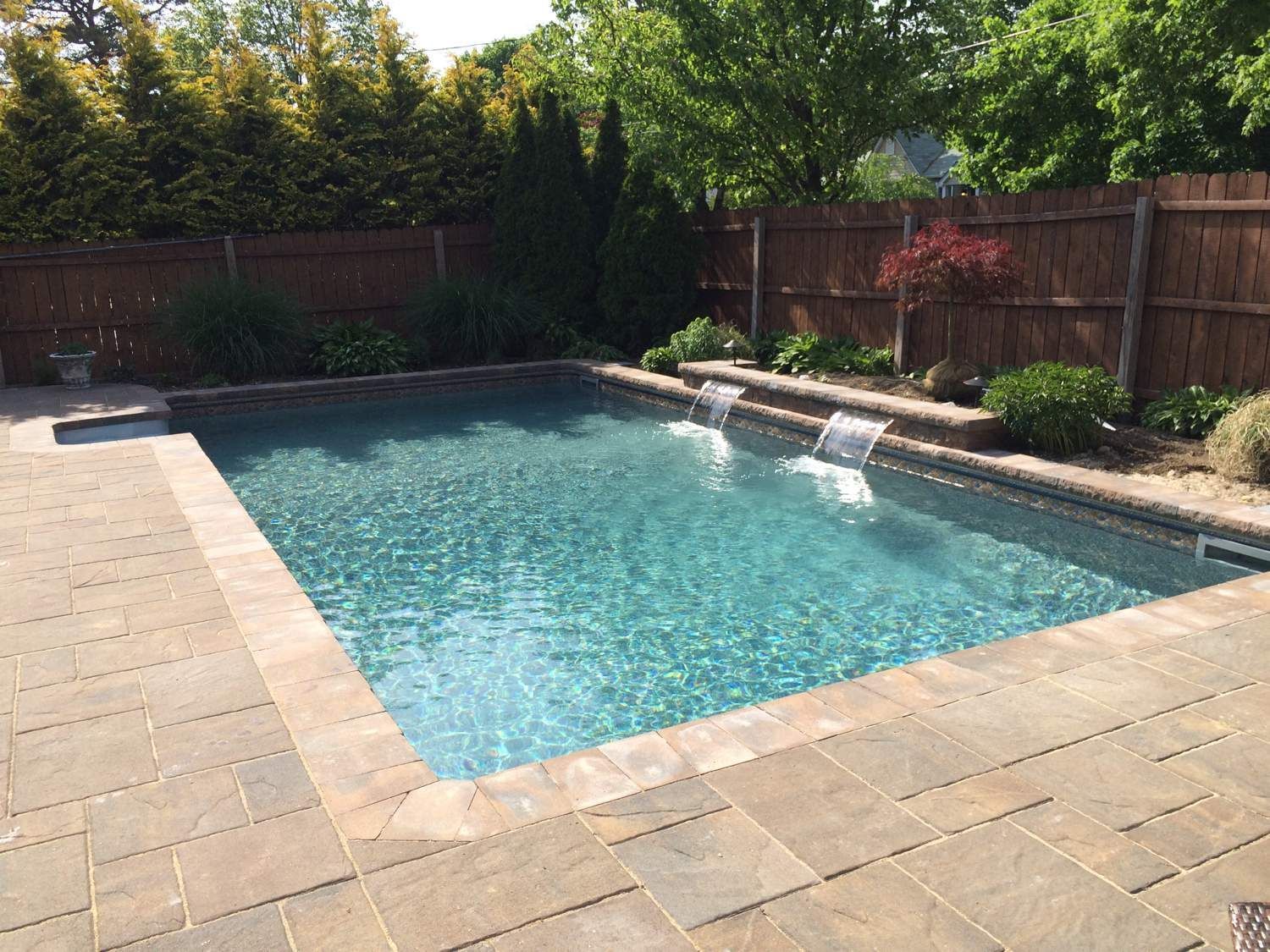 A large swimming pool with a waterfall in the backyard.