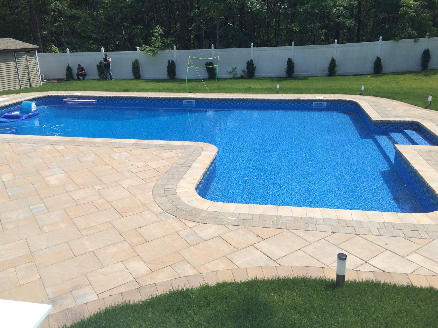 A large swimming pool is surrounded by a brick patio
