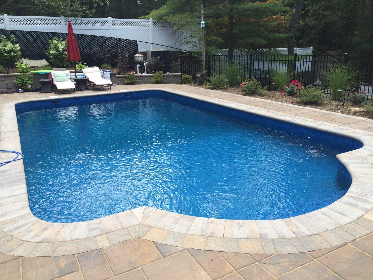 A large swimming pool surrounded by chairs and a fence