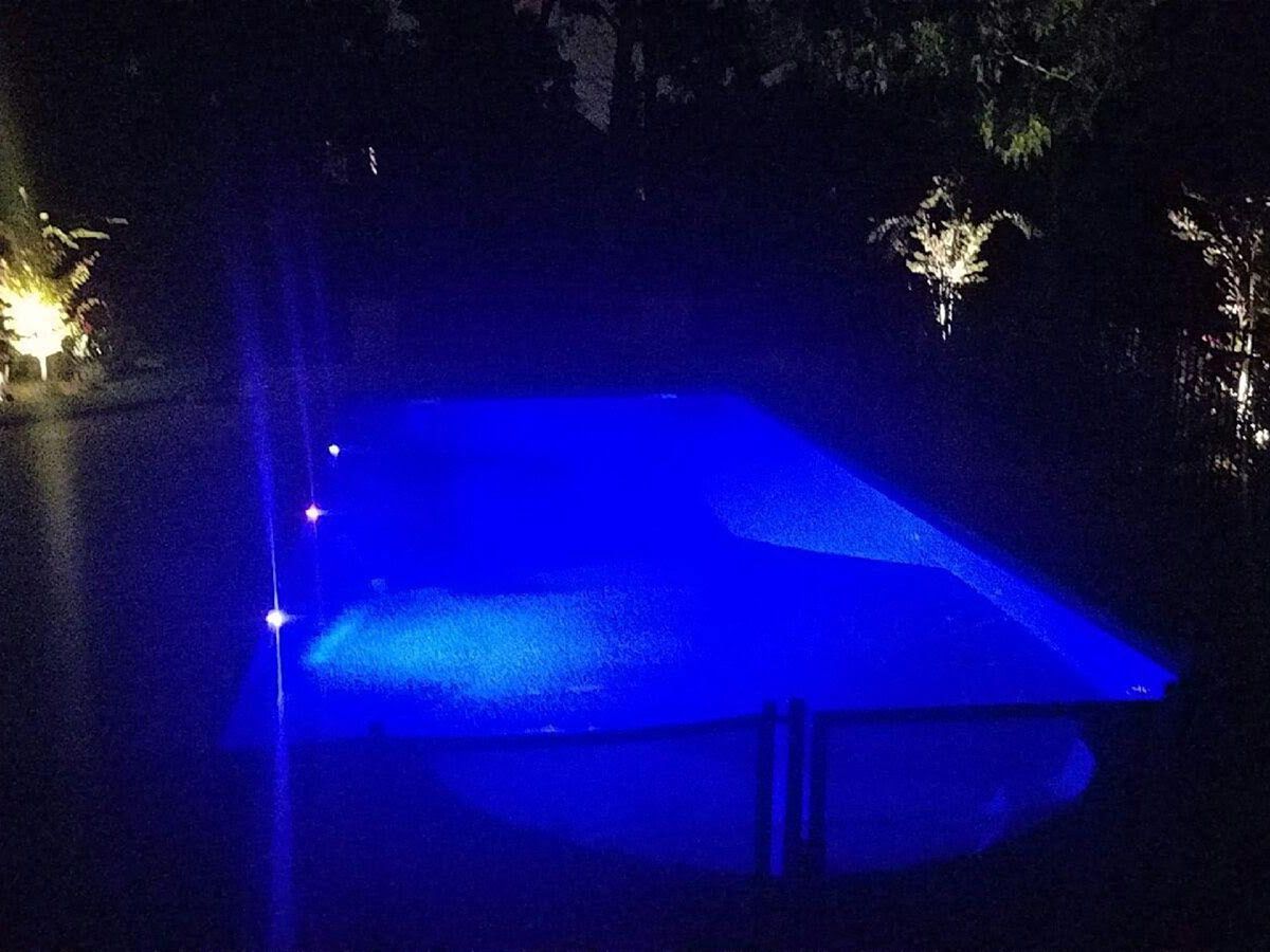 A swimming pool is lit up with blue lights at night
