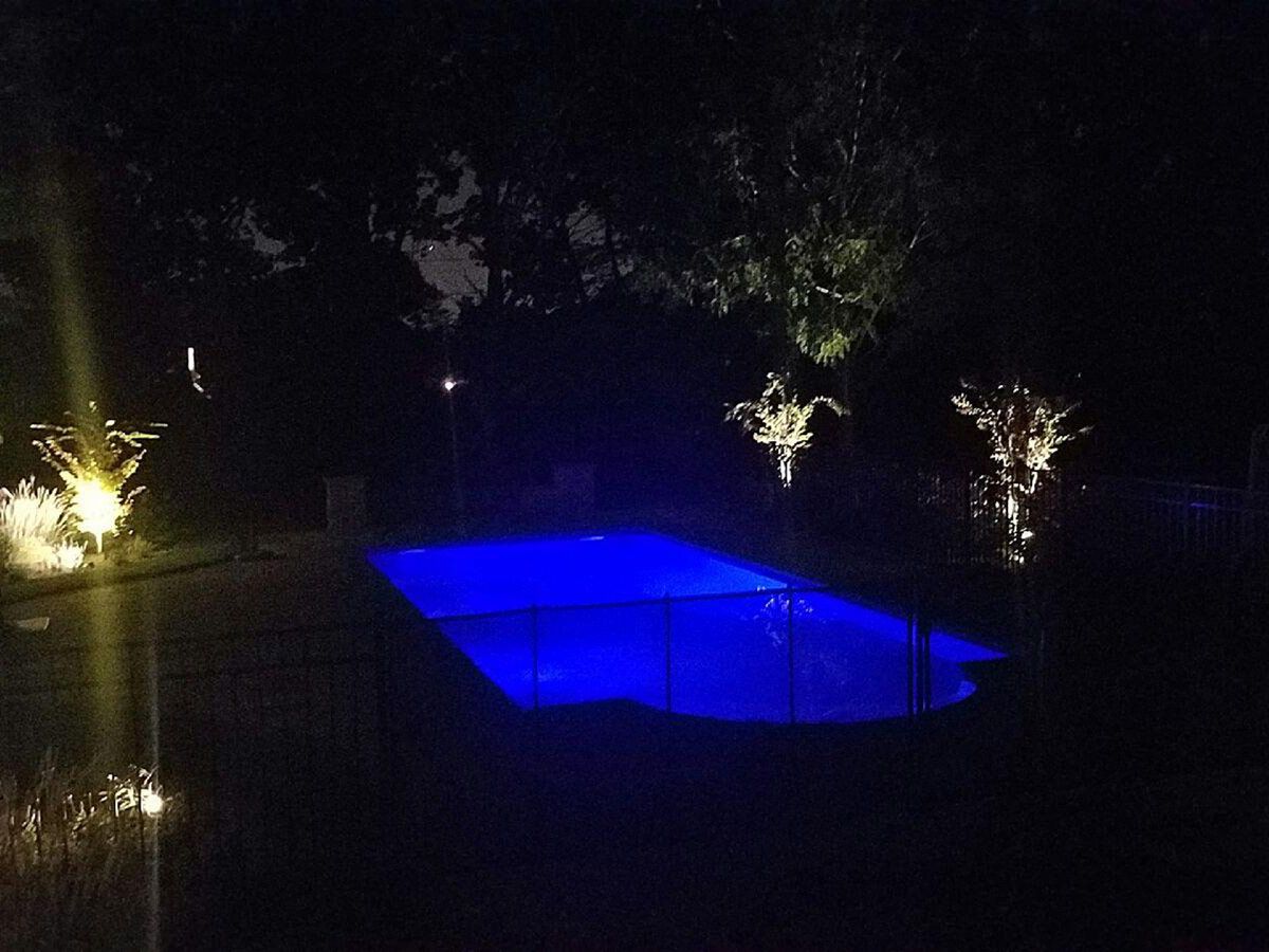 A swimming pool is lit up at night with blue lights