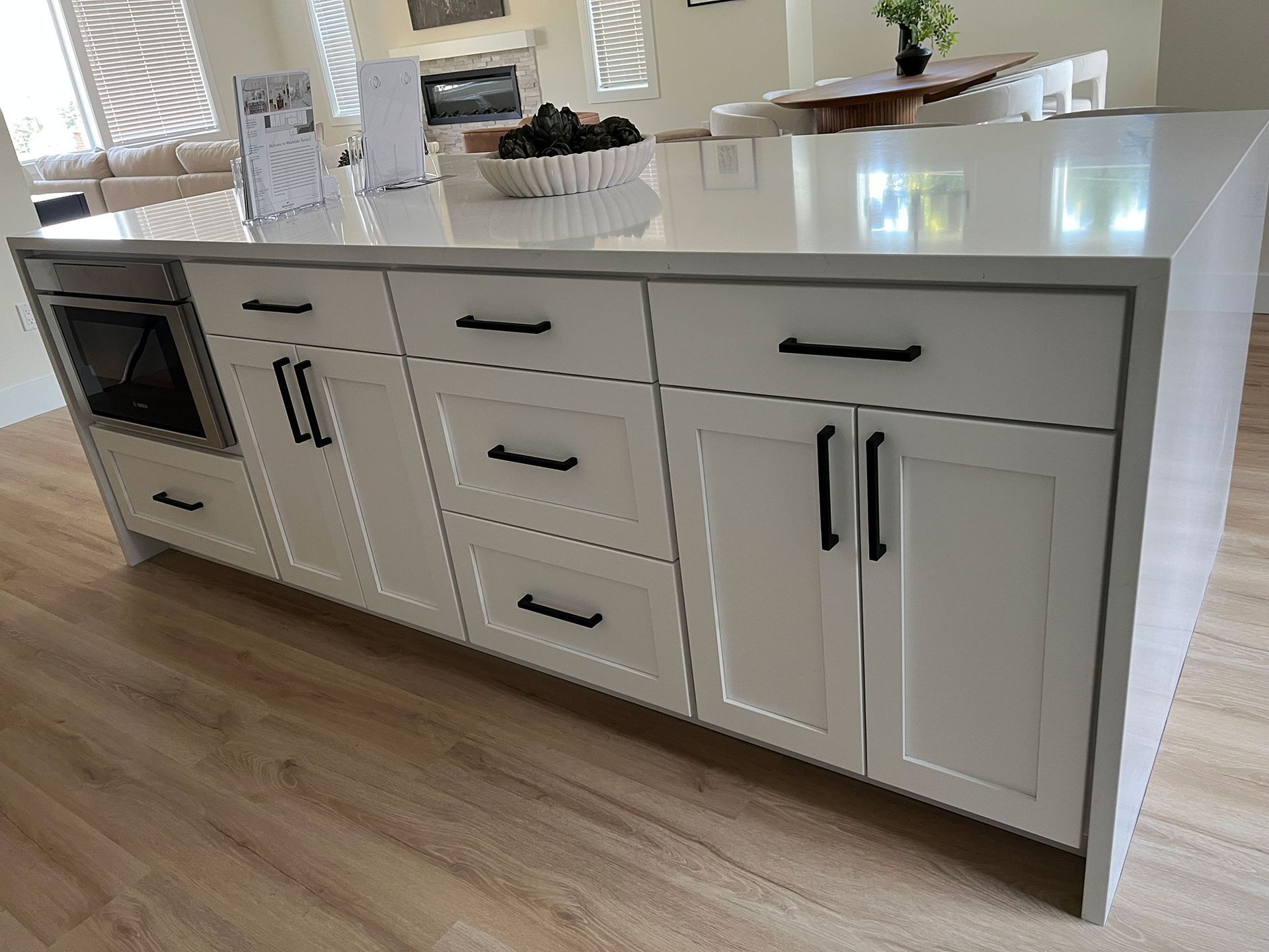 White kitchen island with drawers, cabinets, and a built-in microwave in a bright modern kitchen.