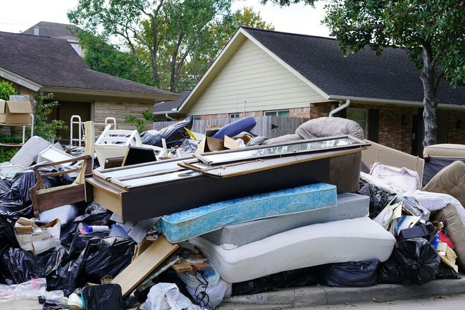 Overflowing pile of discarded furniture and debris in a residential yard after storm damage