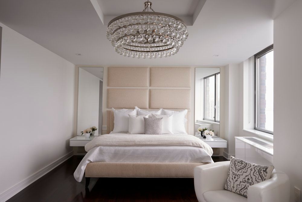 A bedroom with a bed , chair and chandelier.