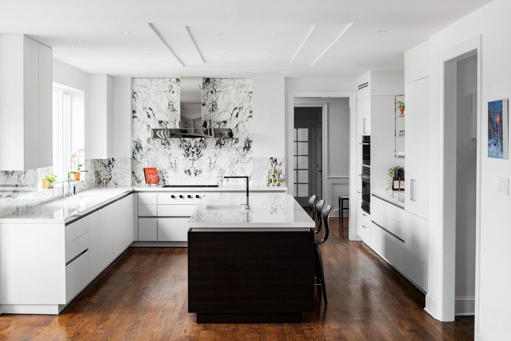 A kitchen with white cabinets and a black island in the middle.