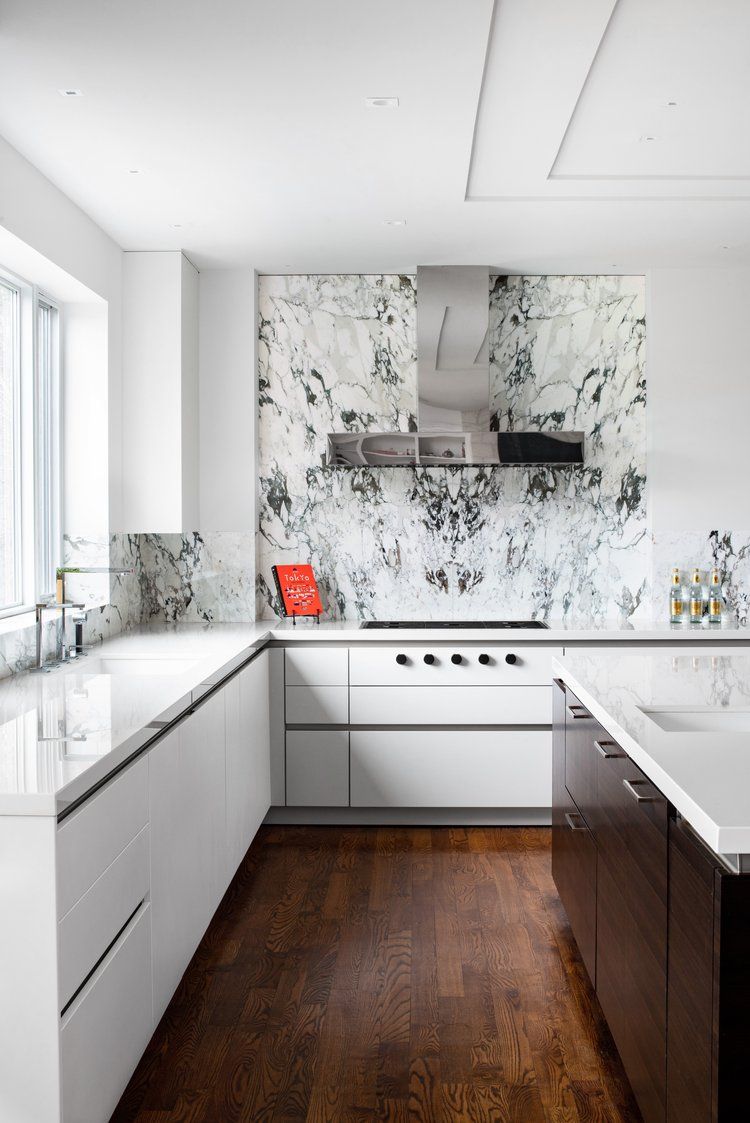 A kitchen with white cabinets , a stove , a sink and a window.