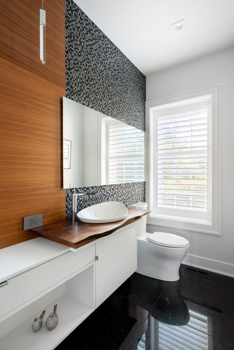 A bathroom with a sink , toilet , mirror and window.