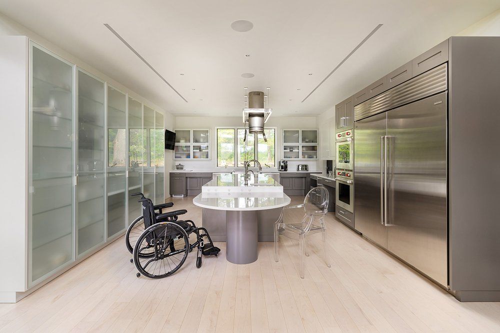 A kitchen with a wheelchair in the middle of it.
