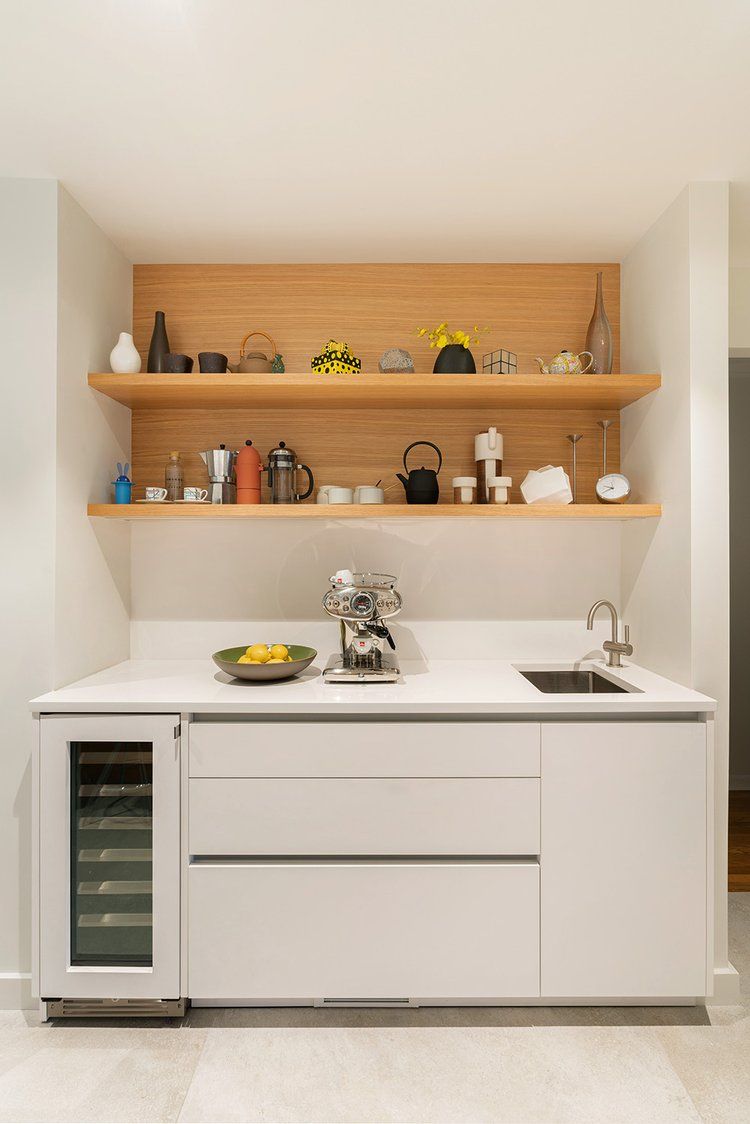 A kitchen with white cabinets and wooden shelves.