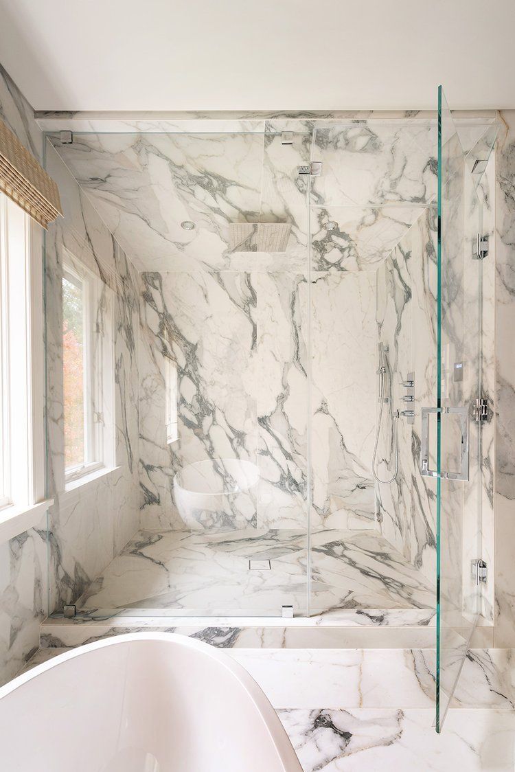 A bathroom with marble walls and a walk in shower.