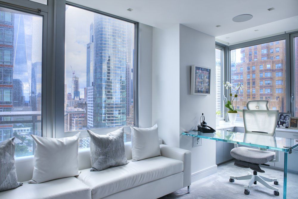 A living room with a couch and a desk with a view of the city.