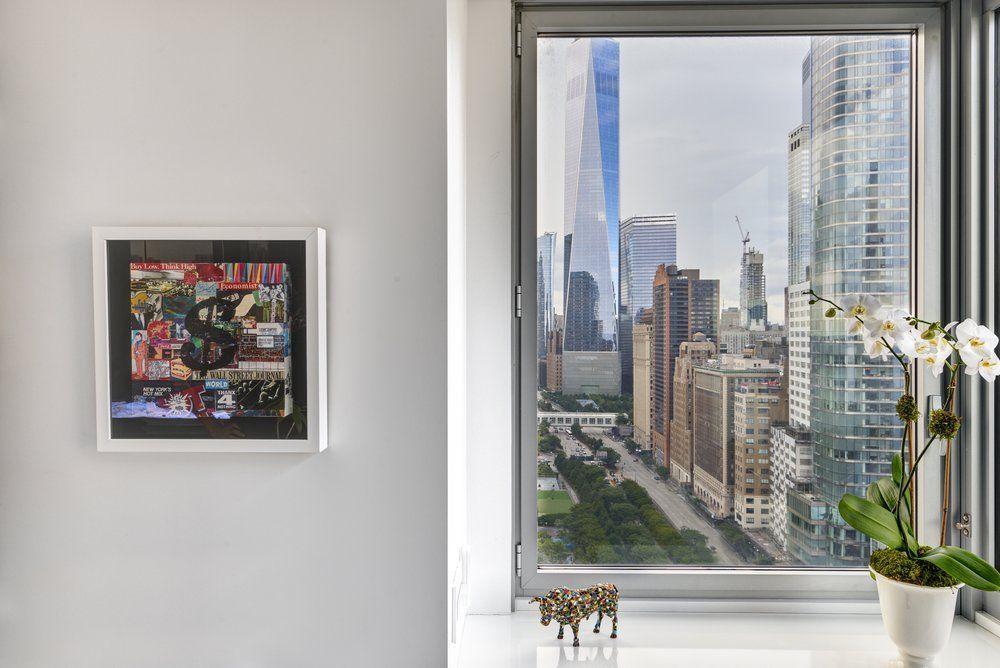 A picture of a city is hanging on a wall next to a window.