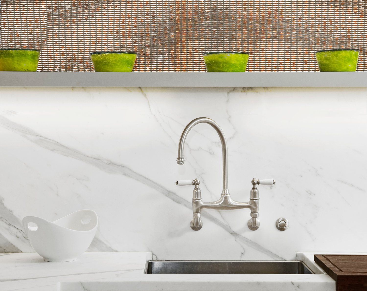 A kitchen sink with a stainless steel faucet and a marble counter top.