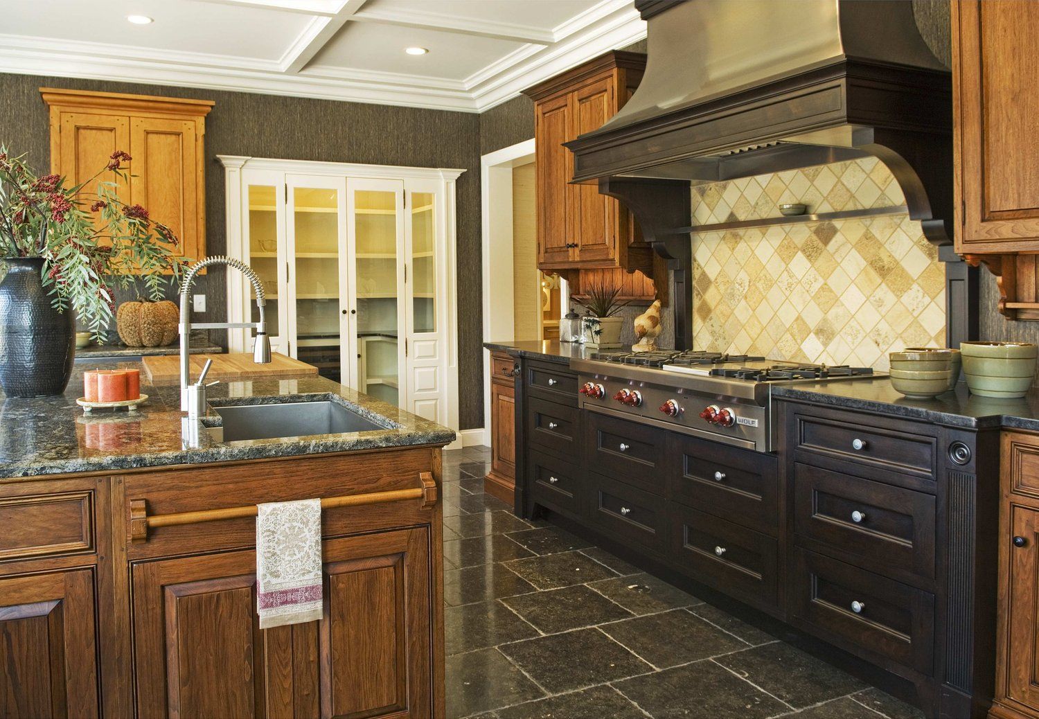 A kitchen with wooden cabinets , granite counter tops , a stove and a sink.