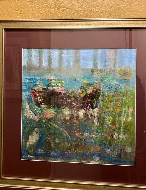 A framed painting of a boat in the water is hanging on a wall.