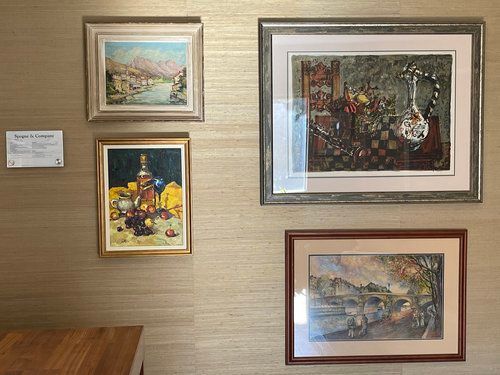 Three framed paintings are hanging on a wall.