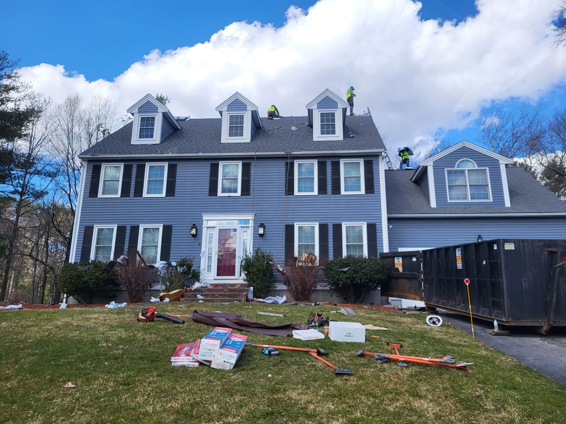 Two men are working on the roof of a large house.