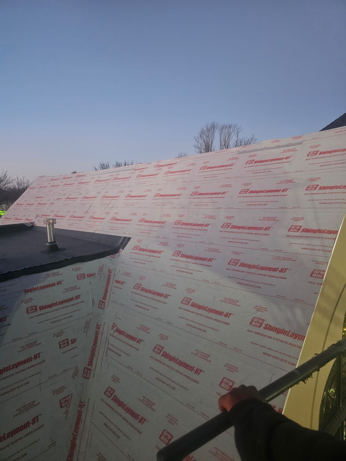 A person is holding a piece of plastic on top of a roof.