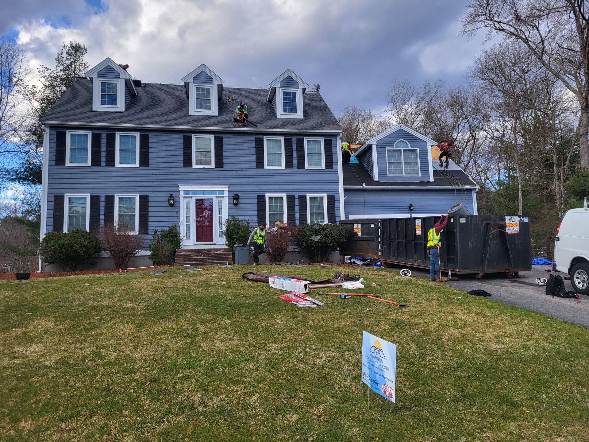 A large blue house with a black roof is being remodeled.