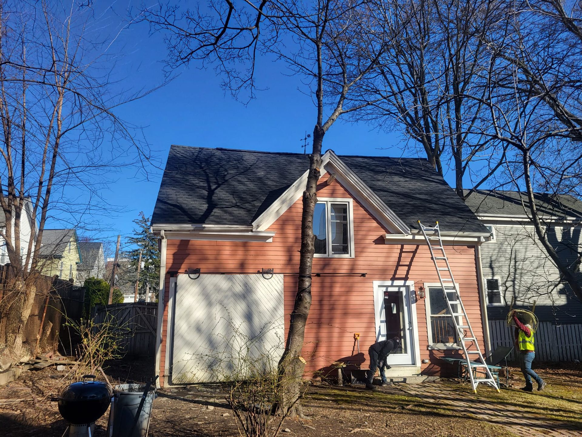 A pink house with a black roof is being painted