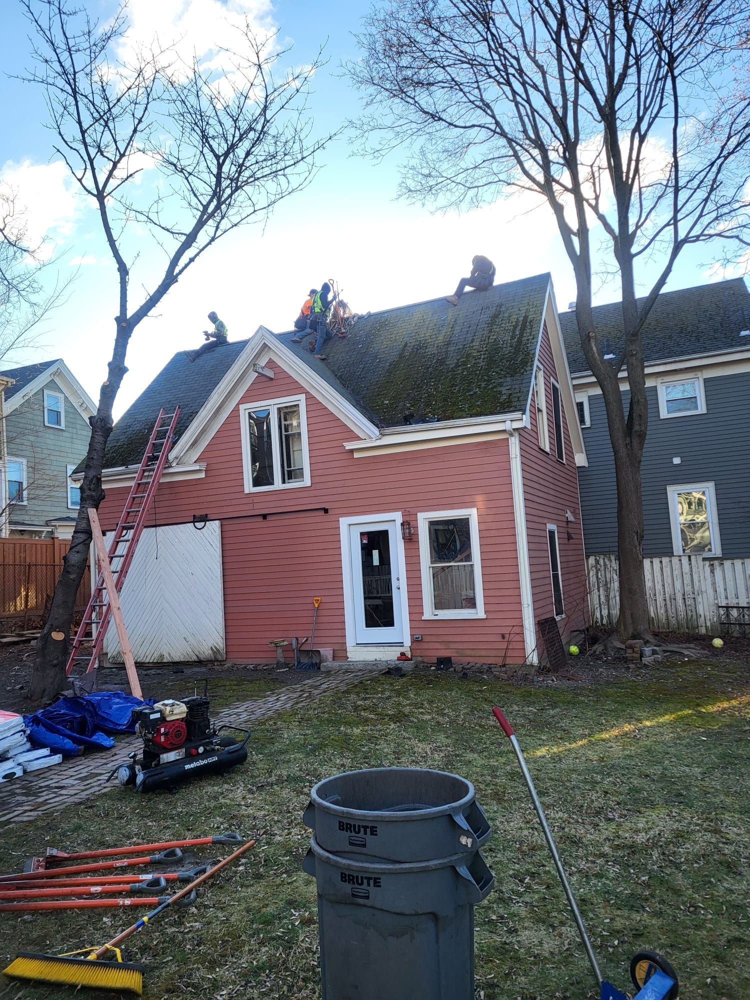 A group of people are working on the roof of a house.