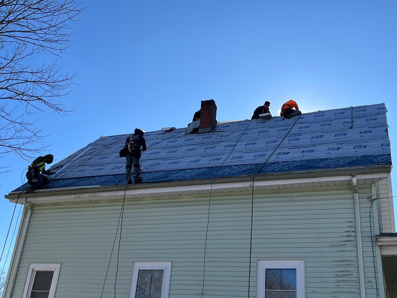 A group of people are working on the roof of a house.