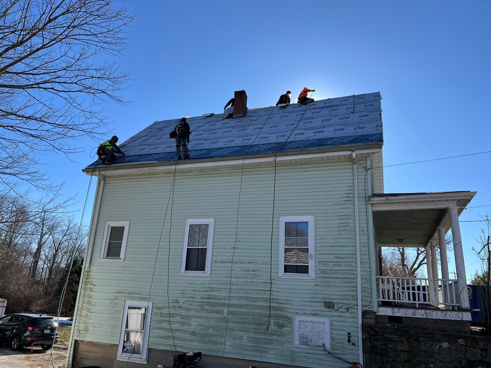 A group of people are working on the roof of a house.