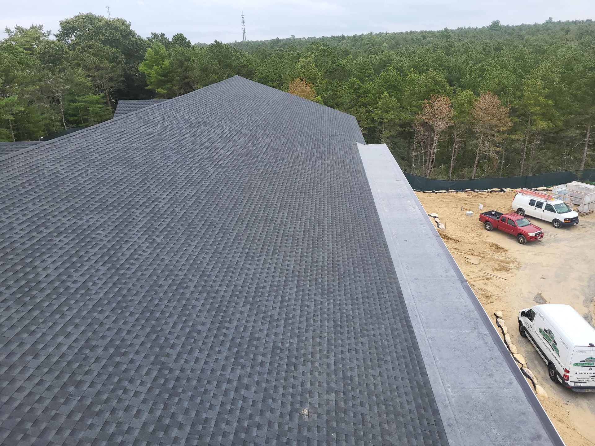 An aerial view of a roof with a lot of trees in the background.