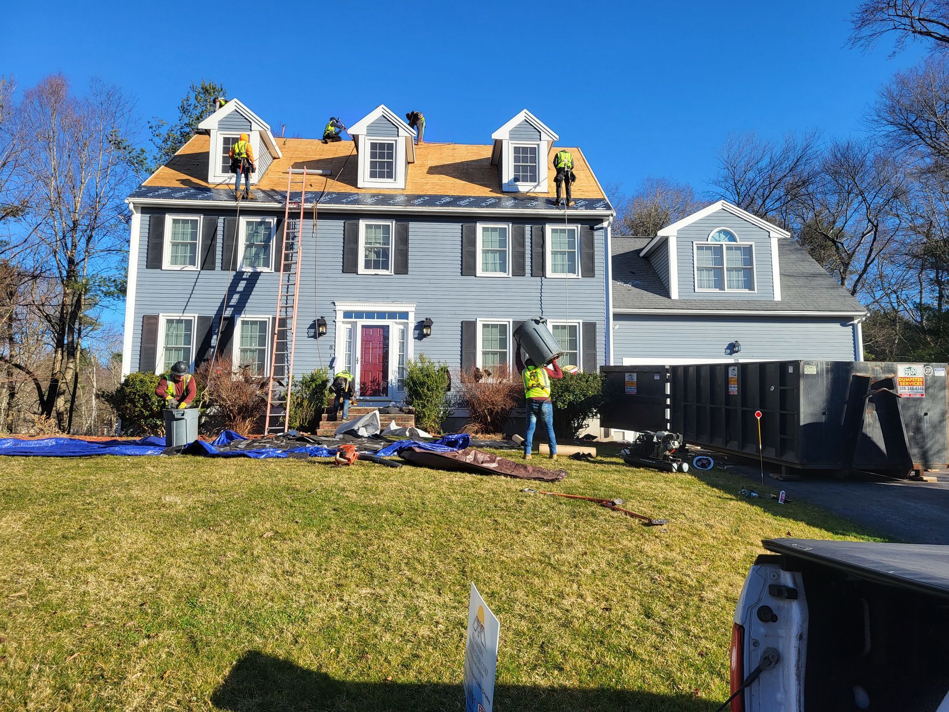A group of men are working on the roof of a large house.