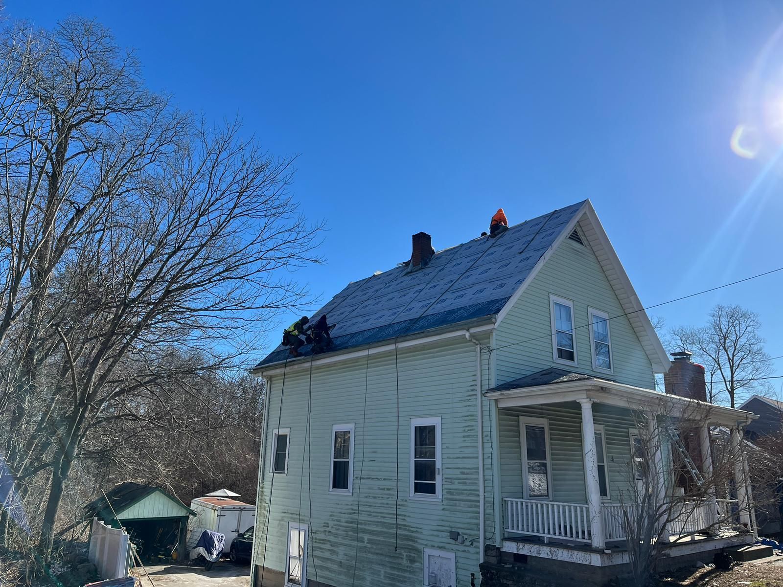 A house with a roof that is being installed on a sunny day.