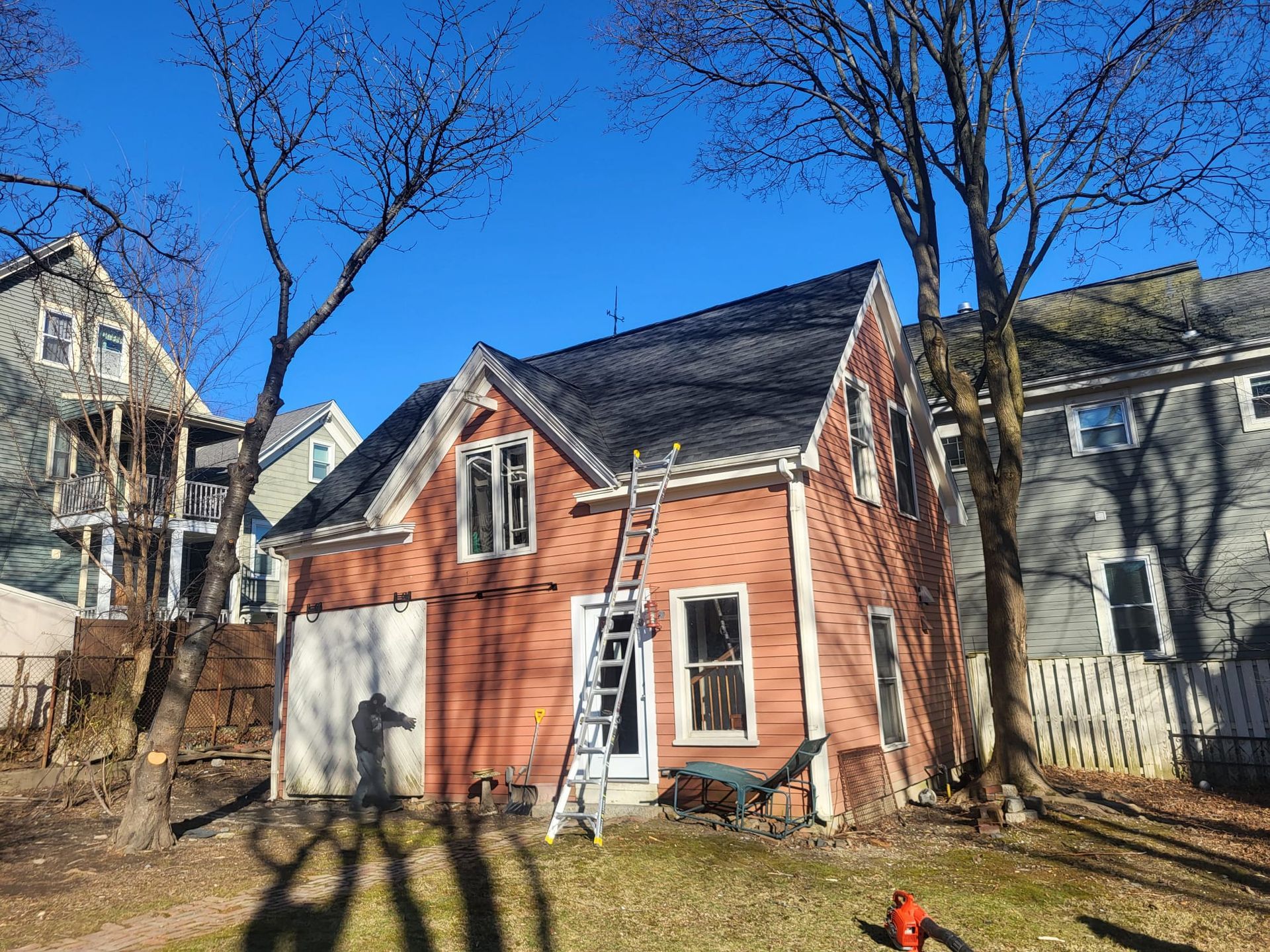 A ladder is sitting in front of a brick house.