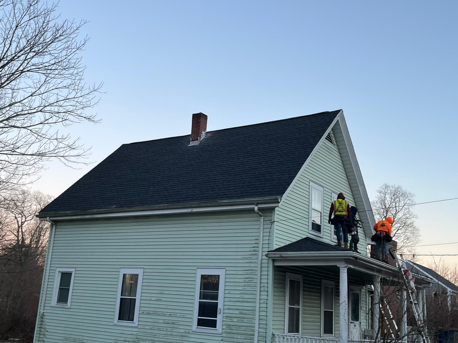 A group of people are working on the roof of a house.