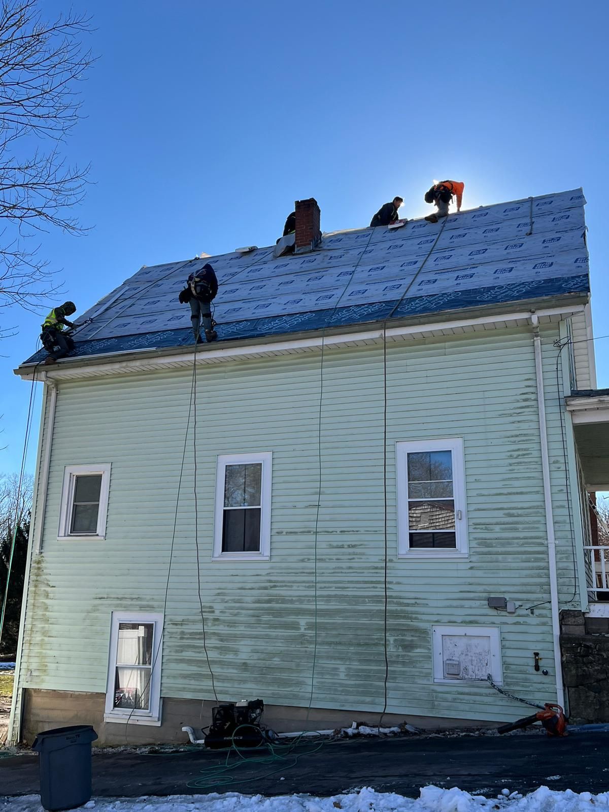 A group of people are working on the roof of a house.