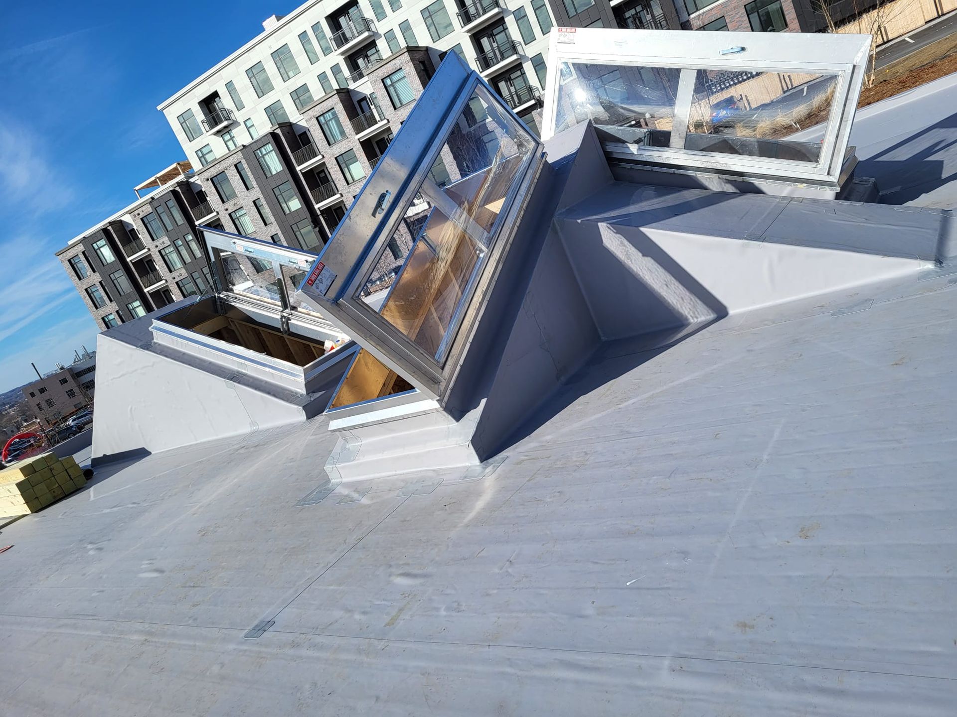 A roof with a skylight on it and a building in the background.