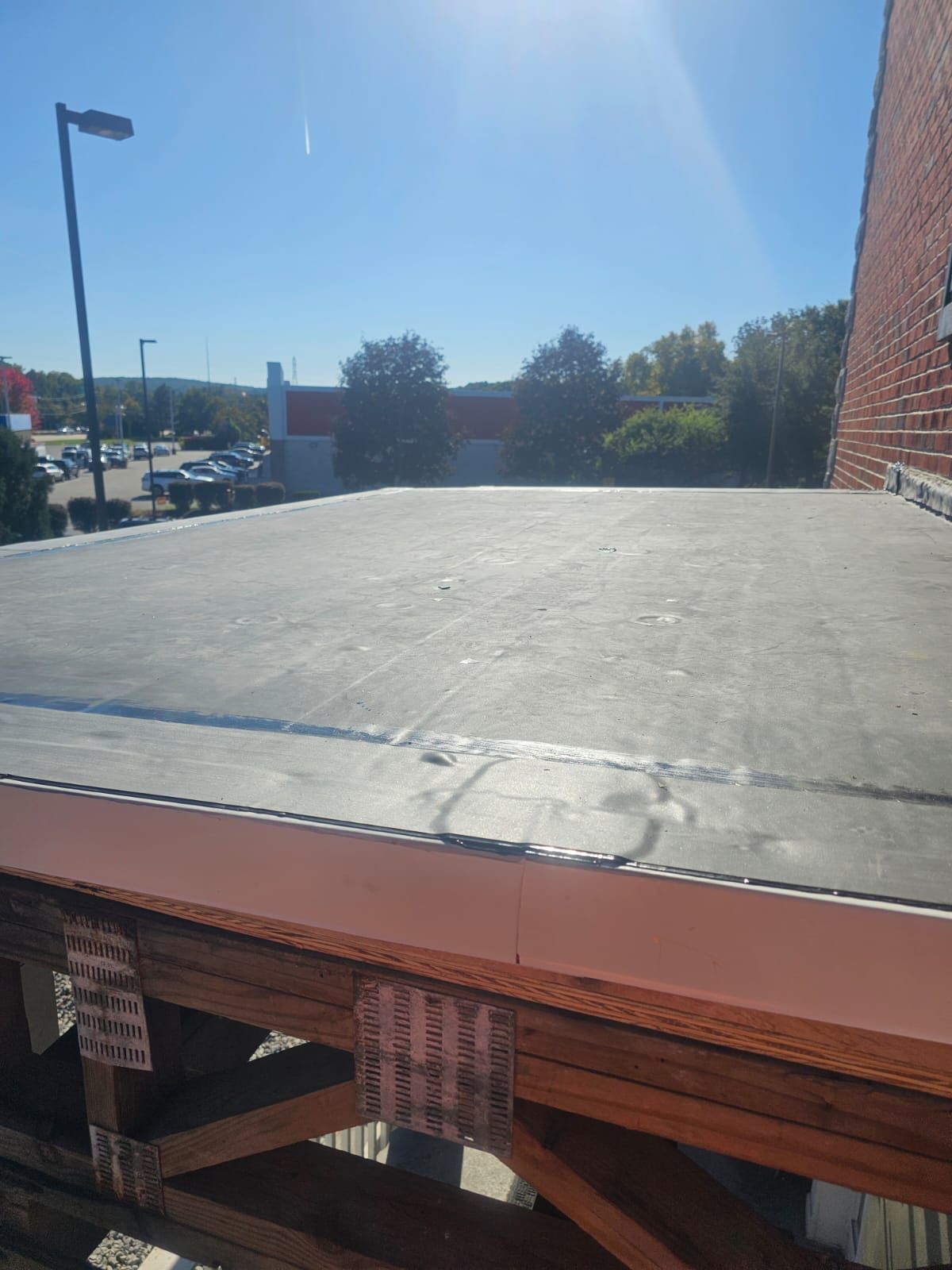 The roof of a building with a wooden deck and a brick building in the background.