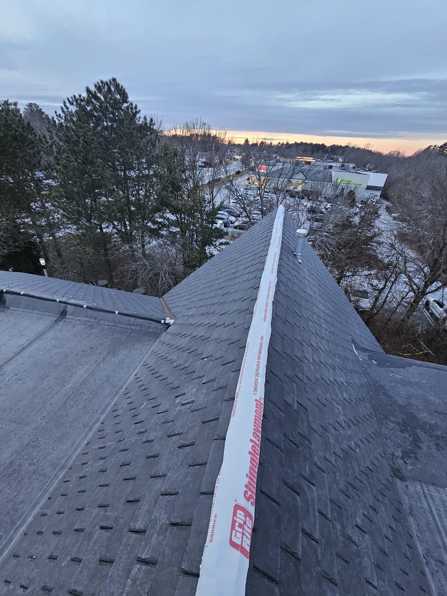 A roof with a row of shingles on it and trees in the background.