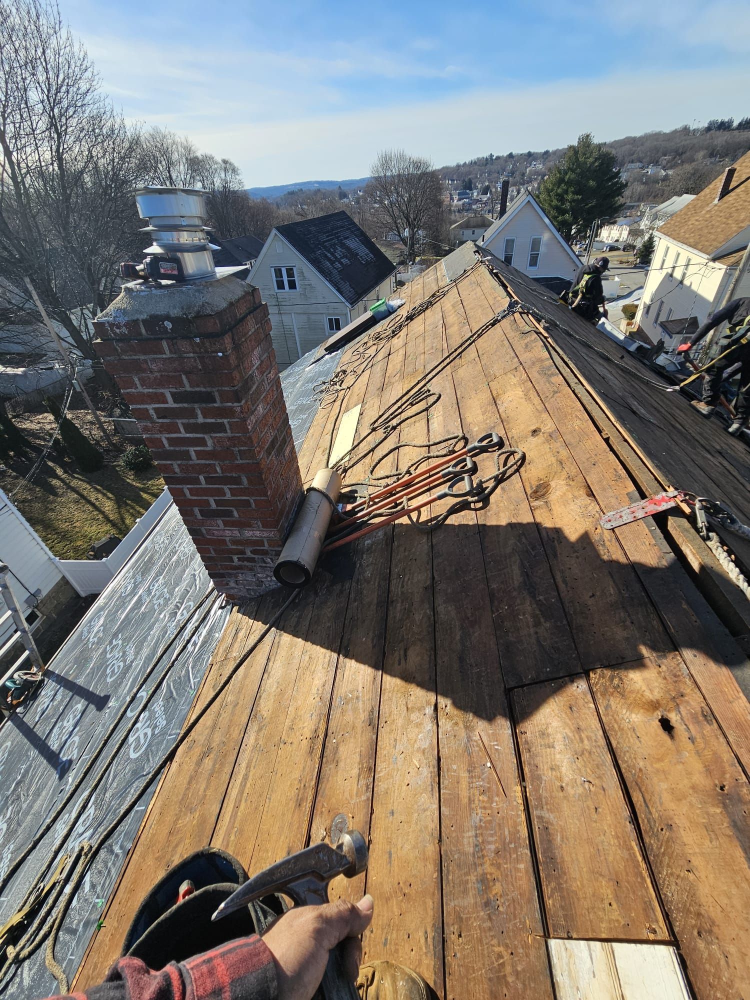 A person is working on a wooden roof with a chimney.