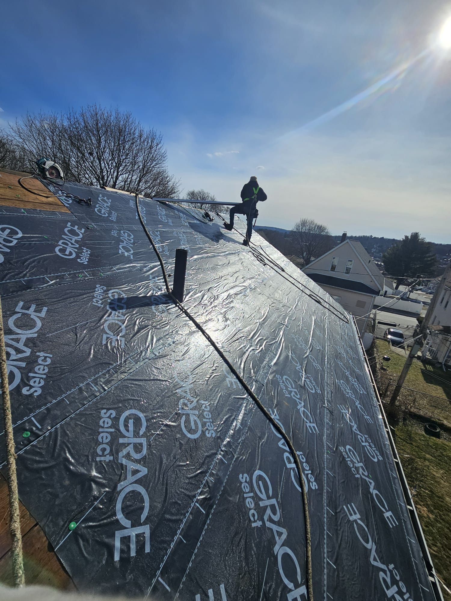 A man is standing on top of a black roof.