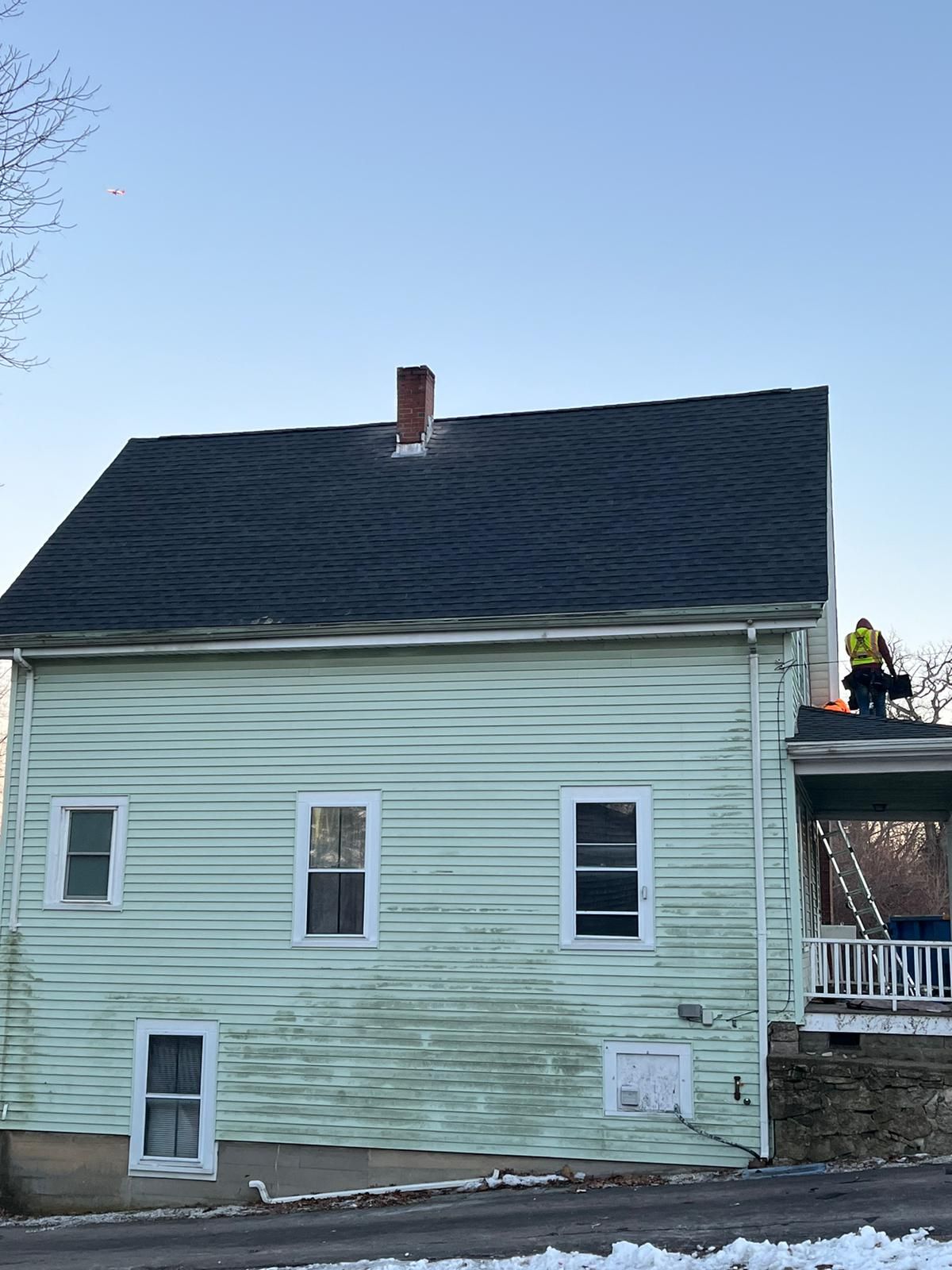 A man is standing on the roof of a green house.