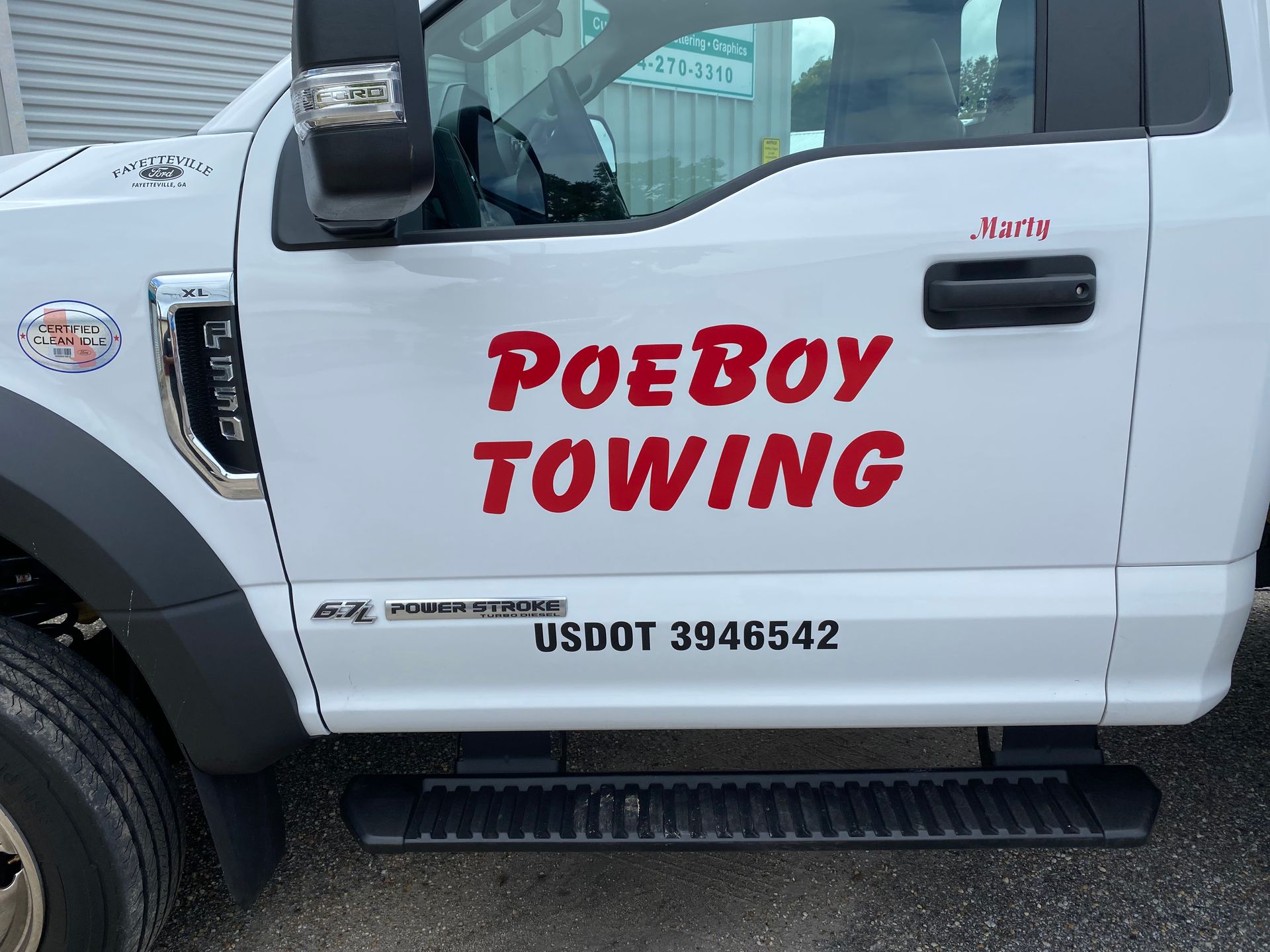 A car with a red signage Poe Boy Towing