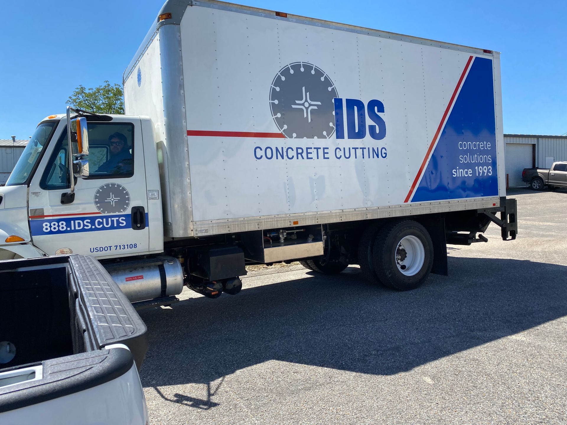 A white truck with blue signage that says IDS Concrete Cutting is parked in a parking lot