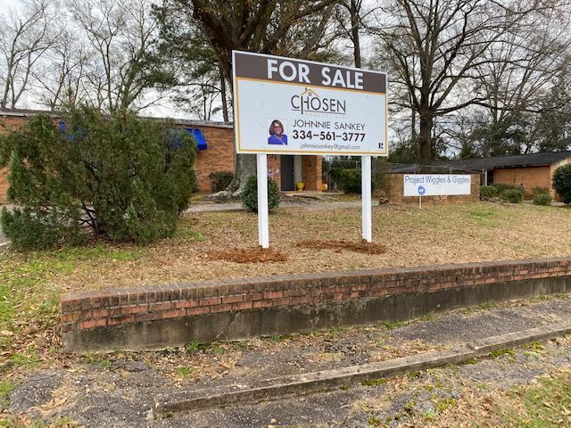A for sale sign is in front of a brick building.