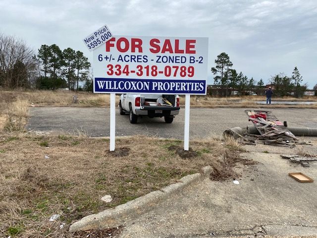 A truck is parked in front of a for sale sign