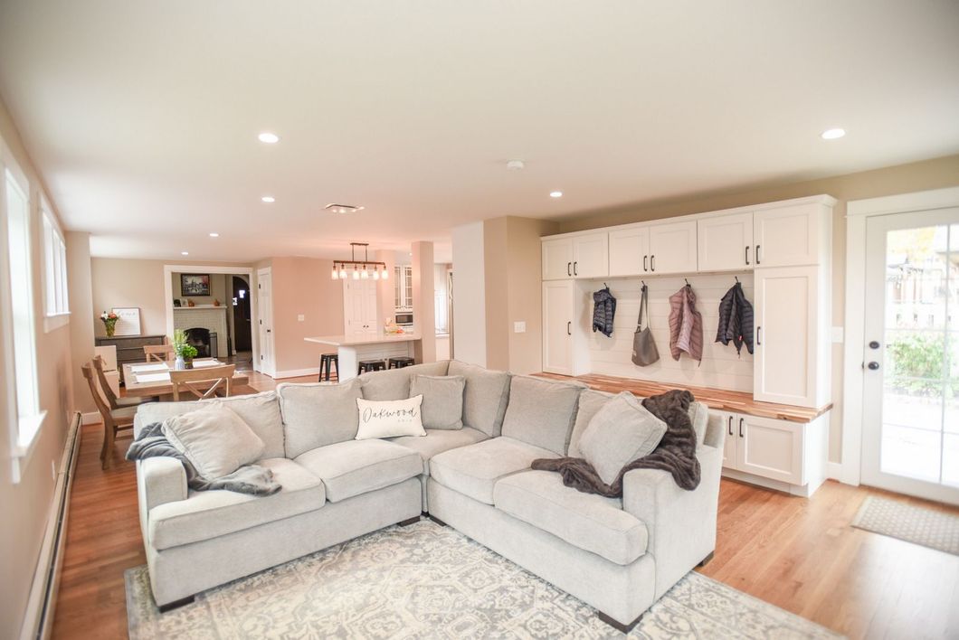 Bright open living room with a gray sectional, white built-ins, and hardwood floors