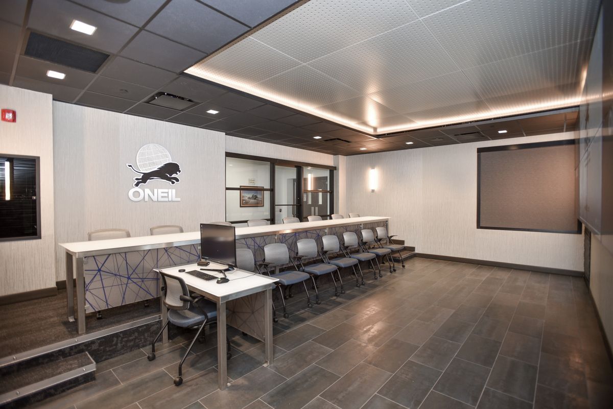 Modern lobby with black chairs, reception desk, and wall-mounted screen in a sleek tiled interior.