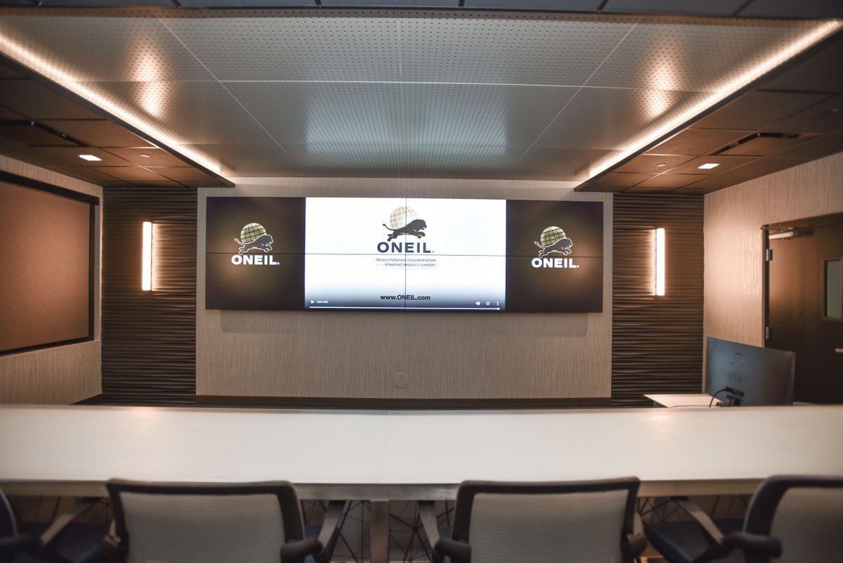Modern conference room with a wall-mounted presentation screen and rows of chairs facing the front.