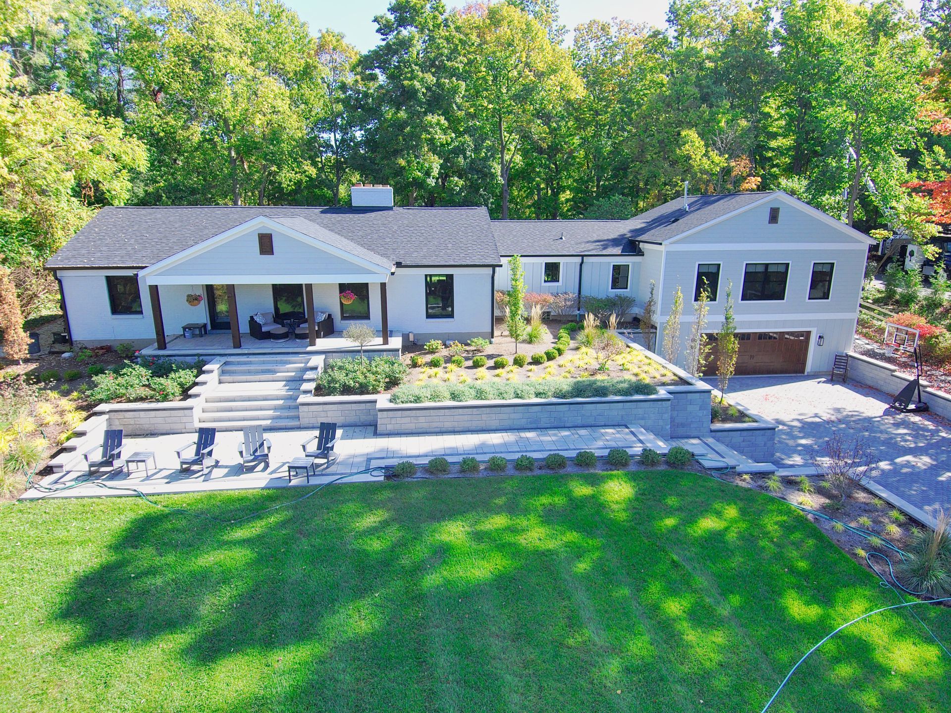 Modern single-story house with white exterior, front patio, and landscaped yard viewed from above.