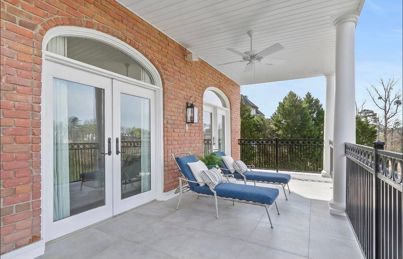 A large porch with a ceiling fan and chairs on it.