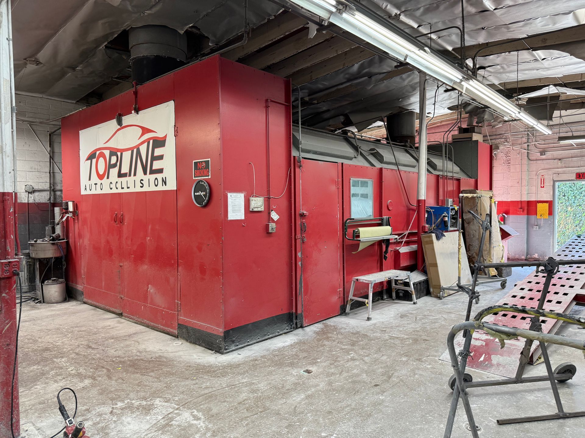 Red Topline Auto Collision paint booth in a garage.
